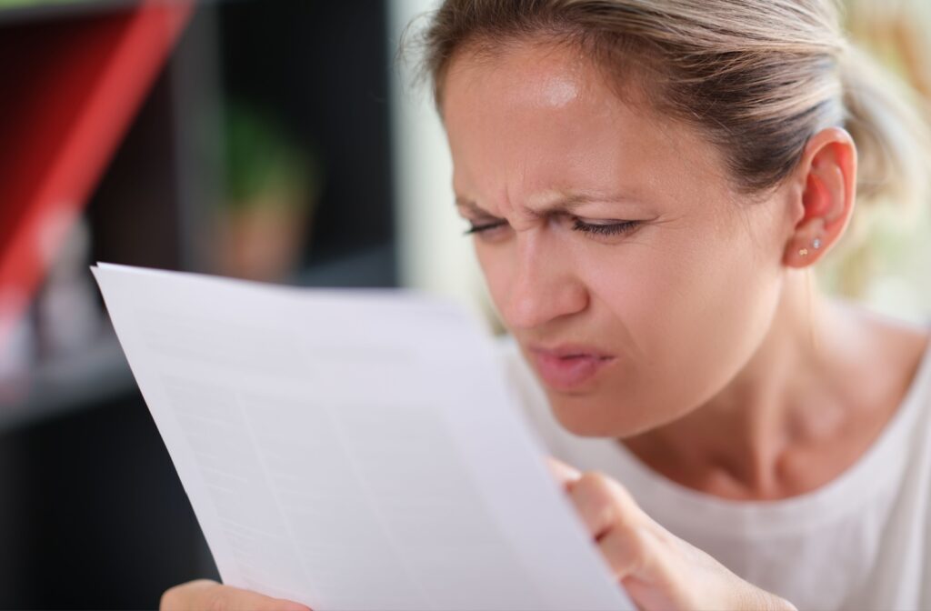A woman squinting and leaning in closer towards a document to see its contents better.
