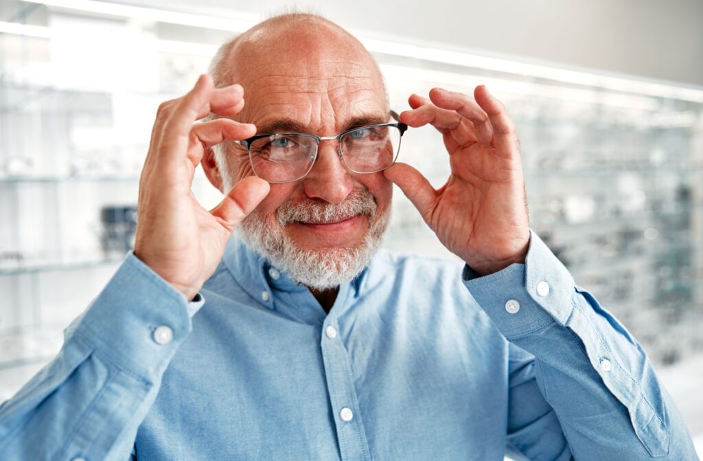 A smiling man adjusts a new and updated pair of eyeglasses on his face.