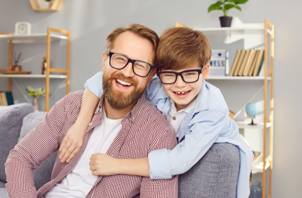 Father and son wearing glasses, smiling after their recent eye exam.