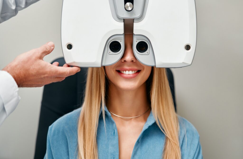 A person smiling during their eye exam while an optometrist tests their vision