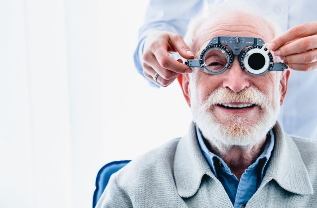 Senior patient smiling at the camera while undergoing an eye exam in a clinic setting.