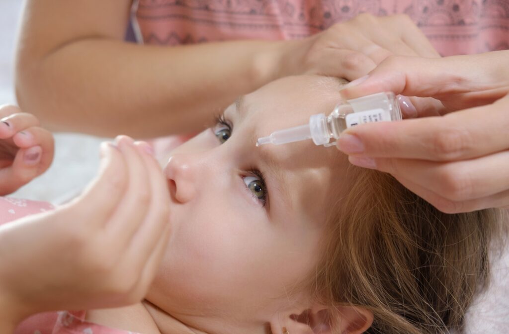 A parent putting in eye drops for pink eye into their child's eye.
