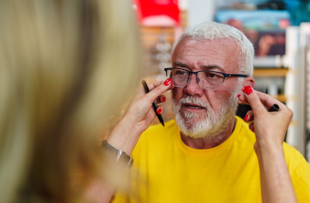 An optician measuring pupil distance on a patient during a glasses fitting.